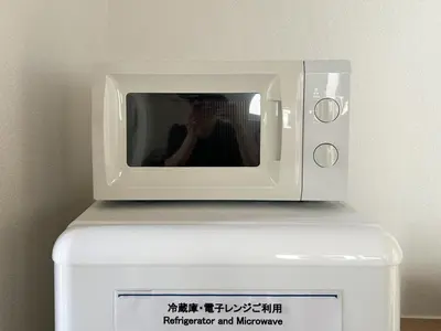 a person taking a picture of a microwave on top of a freezer at \u99c5\u304b\u3089\u5f92\u6b695\u5206\u6c60\u888b\u307e\u3067\u96fb\u8eca\u30675\u5206\u306e\u597d\u7acb\u5730 in Tokyo