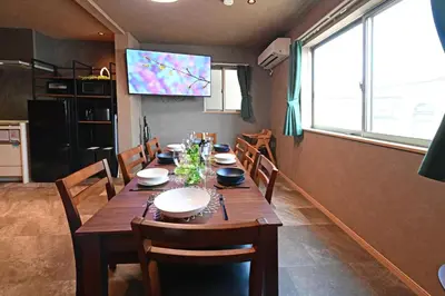 a dining room table with chairs and a television on the wall at Rakuna Inn \u8679 Oshiage2 in Tokyo