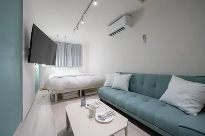 a living room with a blue couch and a bed at RENTO Ikebukuro 101 in Tokyo
