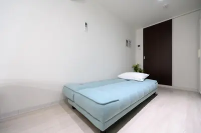 a bedroom with a blue bed in a white room at RENTO Ikebukuro 101 in Tokyo