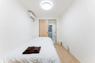 a bedroom with a white bed with two brown towels on it at A quiet residential street with a 5-minute walk from Shirokane Takanawa Station! in Tokyo