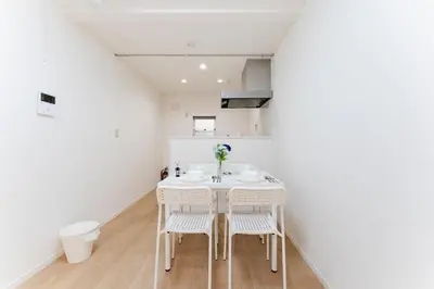 a white dining room with a table and chairs at A quiet residential street with a 5-minute walk from Shirokane Takanawa Station! in Tokyo