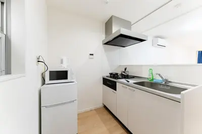 a white kitchen with a sink and a refrigerator at A quiet residential street with a 5-minute walk from Shirokane Takanawa Station! in Tokyo