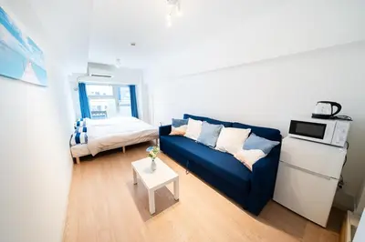 a living room with a blue couch and a bed at Counte Shinjuku in Tokyo