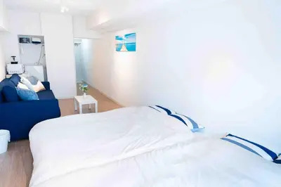 a bedroom with a white bed and a blue couch at Counte Shinjuku in Tokyo