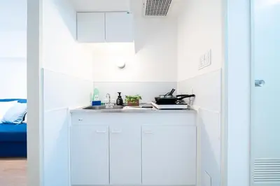 a kitchen with white cabinets and a sink at Counte Shinjuku in Tokyo