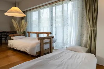 a bedroom with two beds and a large window at The Apartment Hotel Shibuya 1 in Tokyo