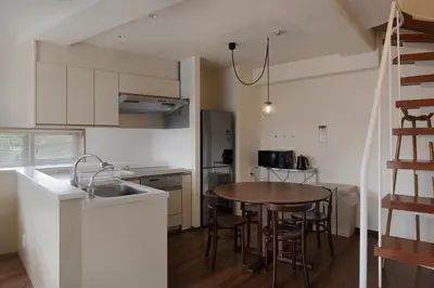 a kitchen with a wooden table and a kitchen with a sink at The Apartment Hotel Yoyogi 1 in Tokyo