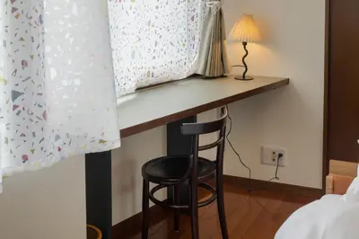 a desk in a bedroom with a stool under a bed at The Apartment Hotel Yoyogi 1 in Tokyo