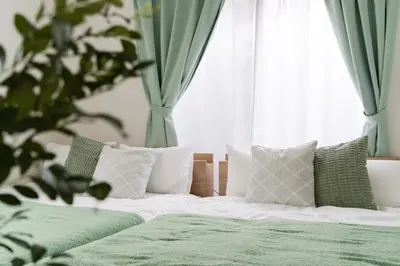 a bed with green sheets and pillows in front of a window at Luxury Tokyo Stay I 120sqm 4LDK I Close to Shibuya & Shinjuku Area in Tokyo