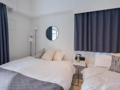 a bedroom with two beds and a mirror at Artessimo \u62bc\u4e0a402 in Tokyo