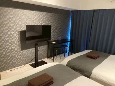 a hotel room with two beds and a flat screen tv at Artessimo \u62bc\u4e0a402 in Tokyo