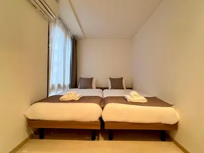 two beds in a small room with a window at Comfy Home Kikukawa in Tokyo