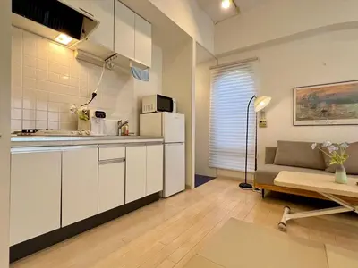 a kitchen with white cabinets and a couch in a room at Comfy Home Kikukawa in Tokyo