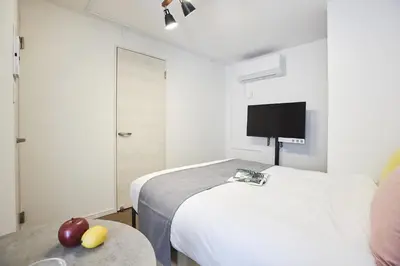 a bedroom with two beds and a tv on the wall at THE Dorchester β in Tokyo