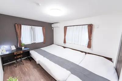 a bedroom with two beds and a desk and two windows at KR family terrace in Tokyo