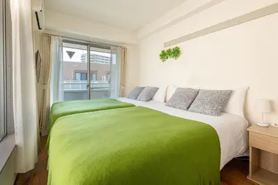 a bedroom with two beds with green sheets and a window at \u30a2\u30b9\u30d4\u30a2403 in Tokyo