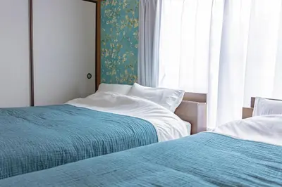 two beds sitting next to each other in a bedroom at tsugumi house \u3064\u3050\u307f\u4ead\u6238\u5efa\u3066\u4eac\u6210\u9ad8\u7802\u99c5 in Tokyo