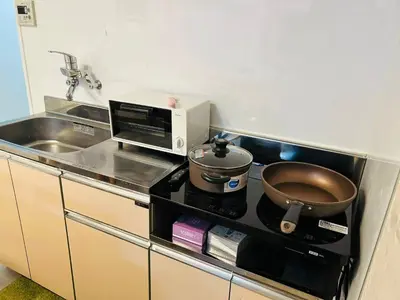 a kitchen with a stove with a pot and a microwave at The Bella Ueno in Tokyo