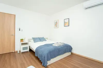 a bedroom with a bed with a blue blanket at Natsumi \u30db\u30c6\u30eb 2F \u6210\u7530\u673a\u573a-\u7fbd\u7530\u673a\u573a-\u4e0a\u91ce \u4e00\u7ebf\u76f4\u8fbe in Tokyo