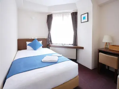 a bedroom with a bed with a blue pillow and a window at POD SELECT HOTEL SHINJUKU - Vacation STAY 43667v in Tokyo