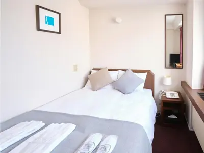 a bedroom with a bed with white sheets and a mirror at POD SELECT HOTEL SHINJUKU - Vacation STAY 43664v in Tokyo