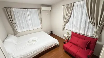 a bedroom with a white bed and a red chair at \u6771\u4eac\u89b3\u5149\u62e0\u70b9 \u30b9\u30ab\u30a4\u30c4\u30ea\u30fc\u773a\u671b \u5c4b\u4e0a\u4ed8\u4e00\u8ed2\u5bb6 \u6700\u592710\u540d \u3086\u3046\u308f\u4ead in Tokyo