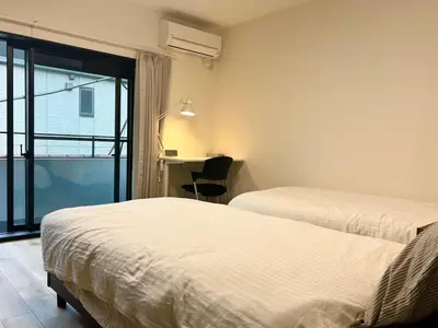 two beds in a room with a desk and a window at 3 Toilets 2 Showers Renovated Shinjuku Large Family Home in Tokyo