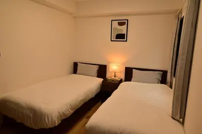 two beds in a small room with a lamp between them at 3 Toilets 2 Showers Renovated Shinjuku Large Family Home in Tokyo