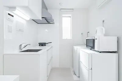 a white kitchen with a microwave and a refrigerator at Subway Higashi Shinjuku Station by 5 mins walk Designer's Apart ment in Tokyo