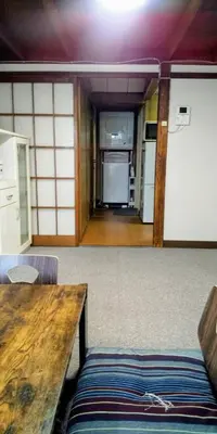 a living room with a wooden table and a kitchen at \u6771\u65b0\u5c0f\u5ca95\u4e01\u76ee in Tokyo