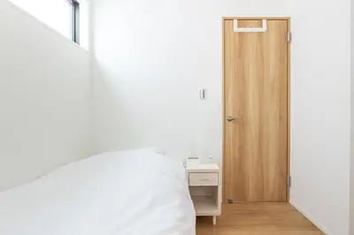 a bedroom with a white bed and a wooden door at JR yamanote line ikebukuro in Tokyo