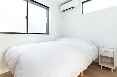 a white bedroom with a bed and a window at JR yamanote line ikebukuro in Tokyo