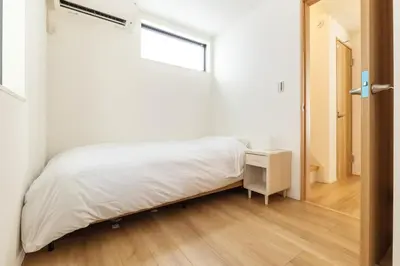a white bedroom with a bed and a window at JR yamanote line ikebukuro in Tokyo