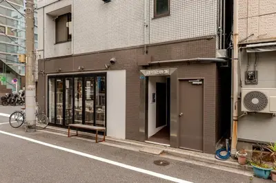 a building with a bench on the side of a street at rot\u6771\u4e0a\u91ce3\u4e01\u76ee302 in Tokyo