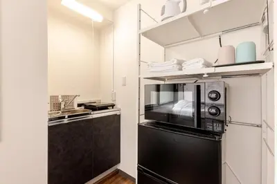 a kitchen with a black refrigerator and a microwave at rot\u6771\u4e0a\u91ce3\u4e01\u76ee302 in Tokyo