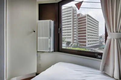 a bedroom with a window with a white bed and a radiator at CraftFlat Komagome 501 a compact studio at excellent location in Tokyo