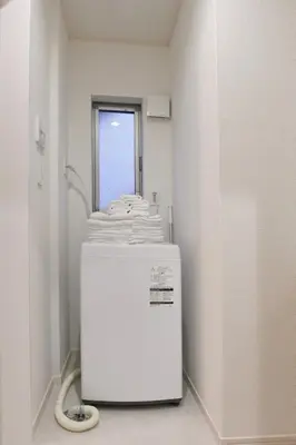 a white refrigerator in a room with a pile of towels at CD199 8 minutes from Ikebukuro in Tokyo