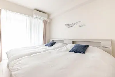 a bedroom with two white beds and a window at tkm\u5143\u9ebb\u5e033\u4e01\u76ee102 in Tokyo