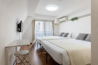 two beds in a room with a table and a chair at \u30a2\u30b9\u30d4\u30a2503 in Tokyo