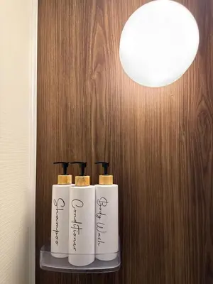 a row of four white bottles on a shelf under a light at Yoyogi Park Retreat in Tokyo