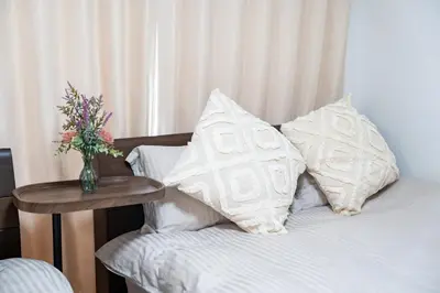 a bed with white pillows and a vase of flowers on a table at \uff48\uff44\uff43\u5927\u585a in Tokyo