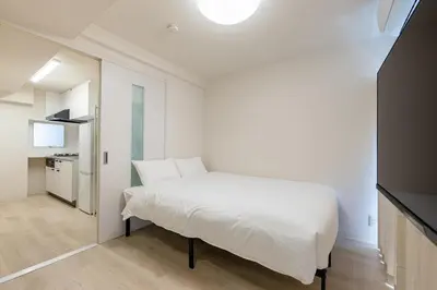 a bedroom with a white bed and a kitchen at \u304b\u3064\u3089303 in Tokyo