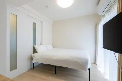a white bedroom with a bed and a tv at \u304b\u3064\u3089303 in Tokyo