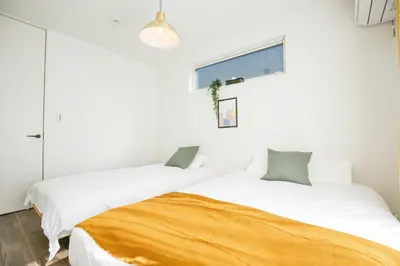 two beds in a room with white walls at SCD2 Ikebukuro Commercial District Premium Homestay in Tokyo