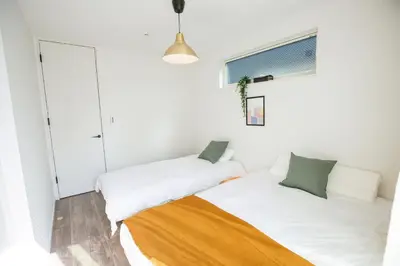 two beds in a room with white walls at SCD2 Ikebukuro Commercial District Premium Homestay in Tokyo