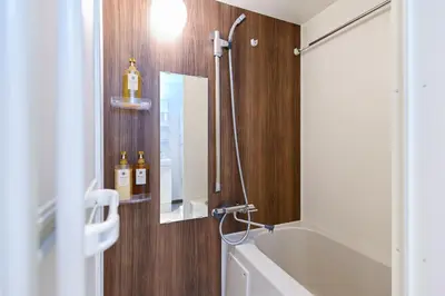 a bathroom with a tub and a shower with a mirror at Evergreen hotel ichigaya in Tokyo