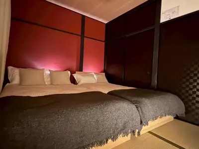 a bedroom with a large bed with a red wall at M&T stay in Tokyo