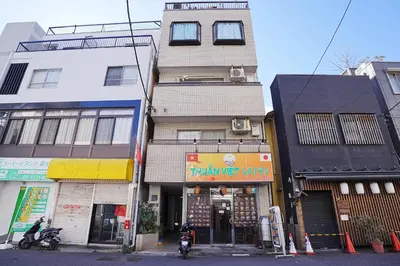a tall building on a city street with buildings at HIKA HOUSE Shinkoiwa in Tokyo