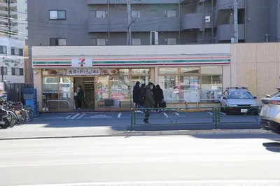 three people walking in front of a gas station at Pr21 \u4e0b\u843d\u5408 in Tokyo